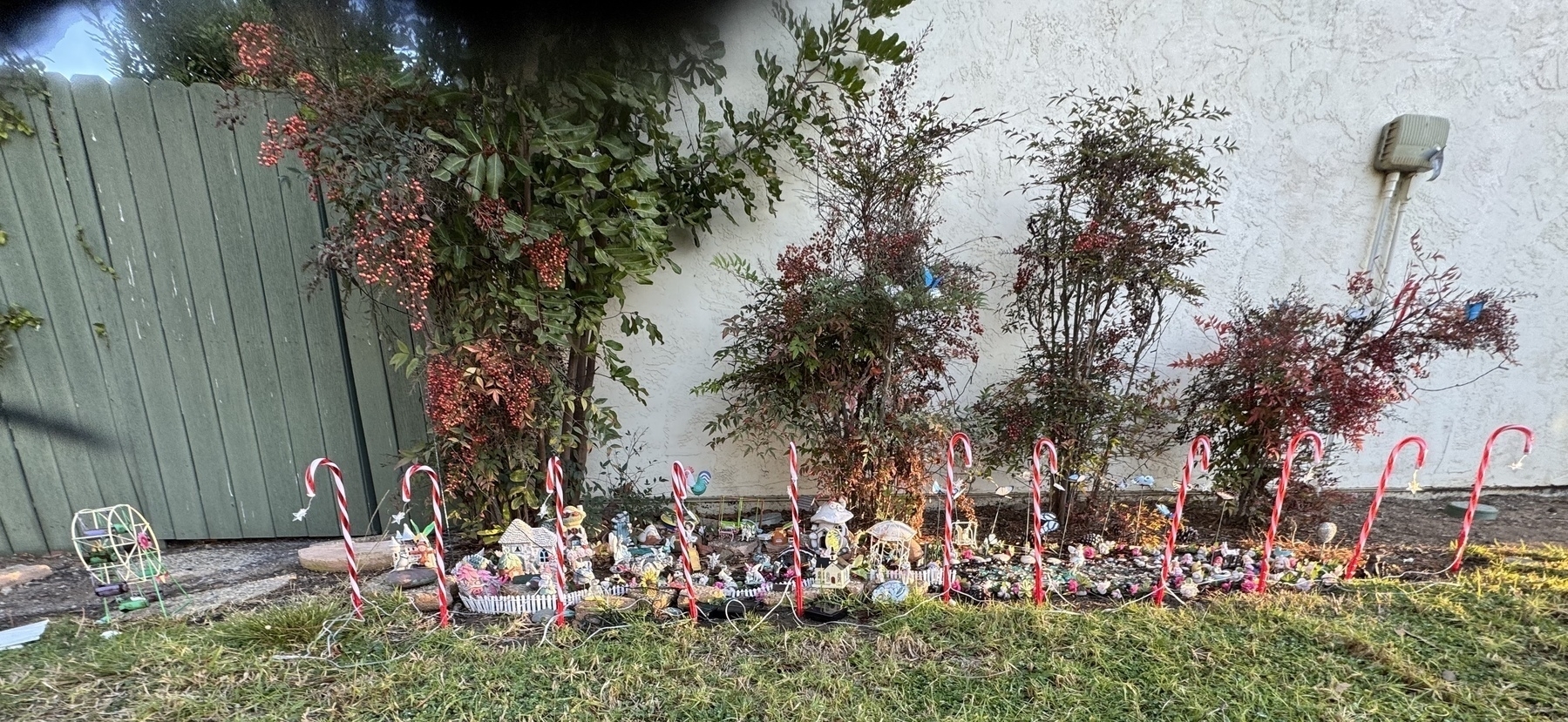 A village of toy houses against the wall on a green lawn, surrounded by candy canes.